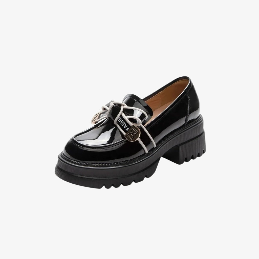 Loafer für Damen in glänzendem Schwarz mit breiten, profilierten Absätzen für einen modernen und mutigen Stil. Eine Dekoration mit weißen Schnürsenkeln und goldfarbenen Metallverzierungen auf dem Oberteil setzt einen eleganten und originellen Akzent bei diesen schicken und bequemen Schuhen.