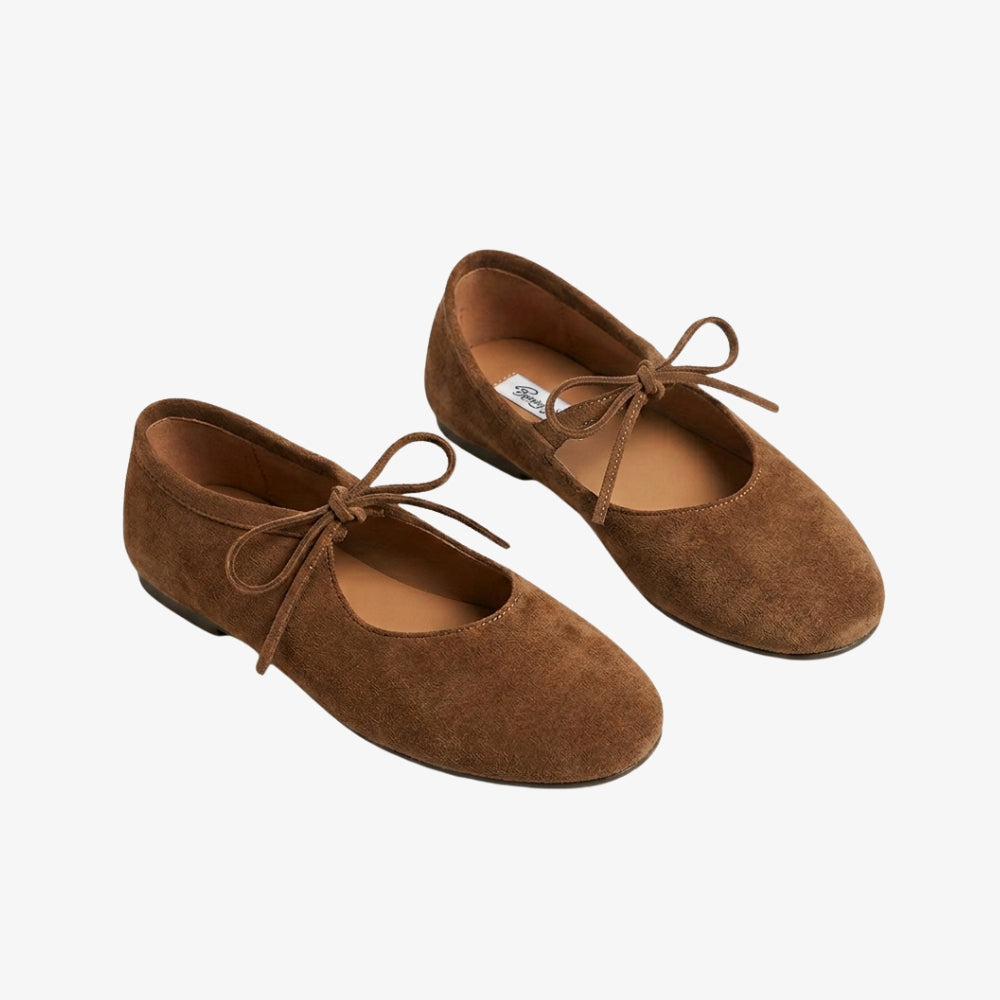 Loafer-Ballerina aus cognacbraunem Kunstwildleder mit einer Schleife auf der Vorderseite, vor grauem Hintergrund