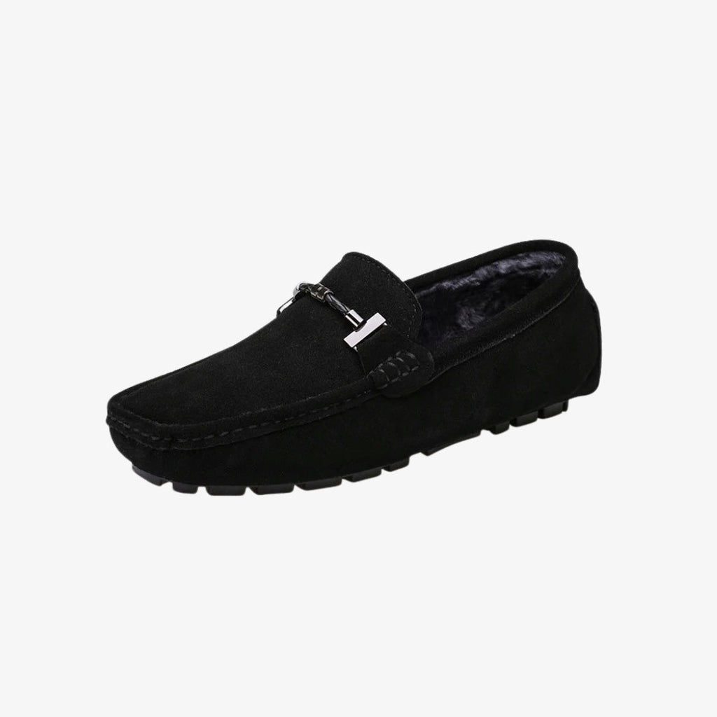 Loafer für Herren aus schwarzem Wildleder, mit weichem Material gefüttert für mehr Komfort. Das klassische Design wird durch eine silberfarbene Metallschnalle auf der Oberseite aufgewertet. Die profilierte Sohle bietet guten Halt und verbindet Stil und Funktionalität.