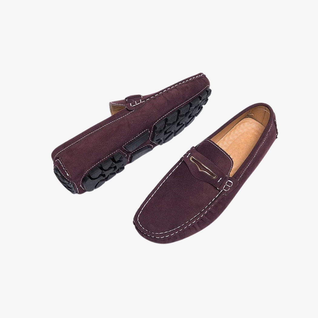 Bequeme Loafer für Herren aus Wildleder in Burgunderrot. Diese eleganten Schuhe haben weiße Kontrastnähte, eine dezente Metallschnalle auf dem Schaft und eine schwarze Profilsohle für besseren Halt. Das gepolsterte Innere sorgt im Alltag für optimalen Komfort.
