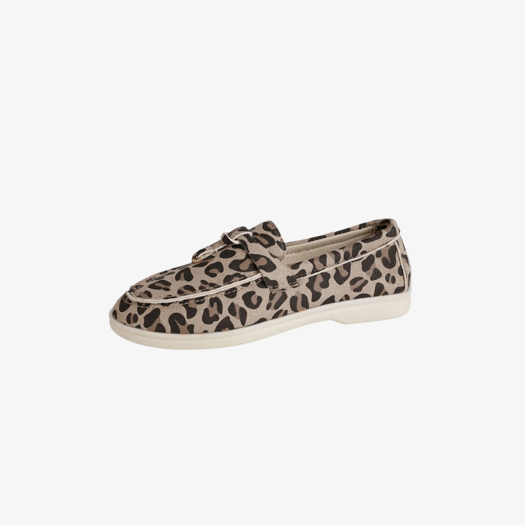 Damen-Mokassins aus Wildleder mit elegantem Leopardenmuster. Die leichten und bequemen Schuhe haben eine dezente weiße Sohle und ein dekoratives Riemchen auf dem Spann, perfekt für einen lässigen und trendigen Stil.