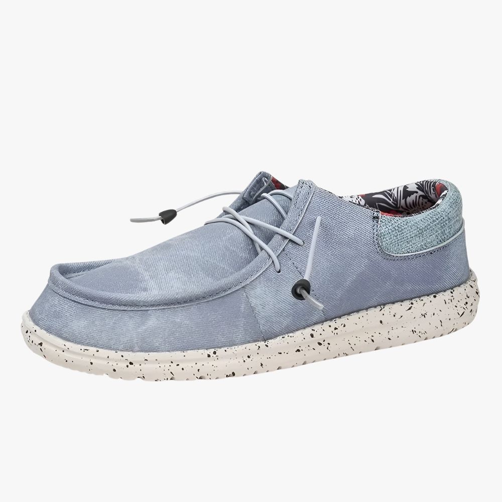 Loafer aus blauem Stoff mit weißen Sohlen. Das Innenfutter ist ein Stoff mit Blumenmuster.
