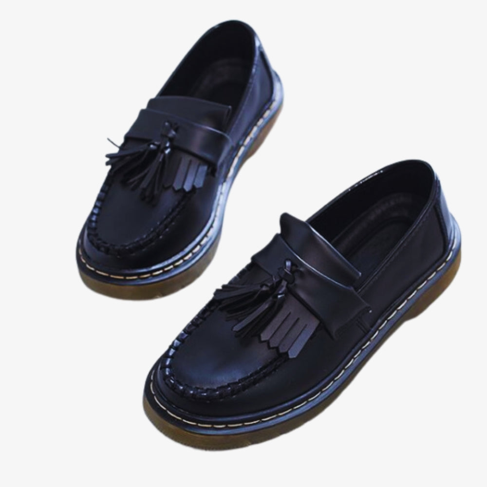 Auf weißem Hintergrund ist ein Paar Damen-Loafer mit Quasten und Fransen aus Kunstleder zu sehen, sie sind schwarz