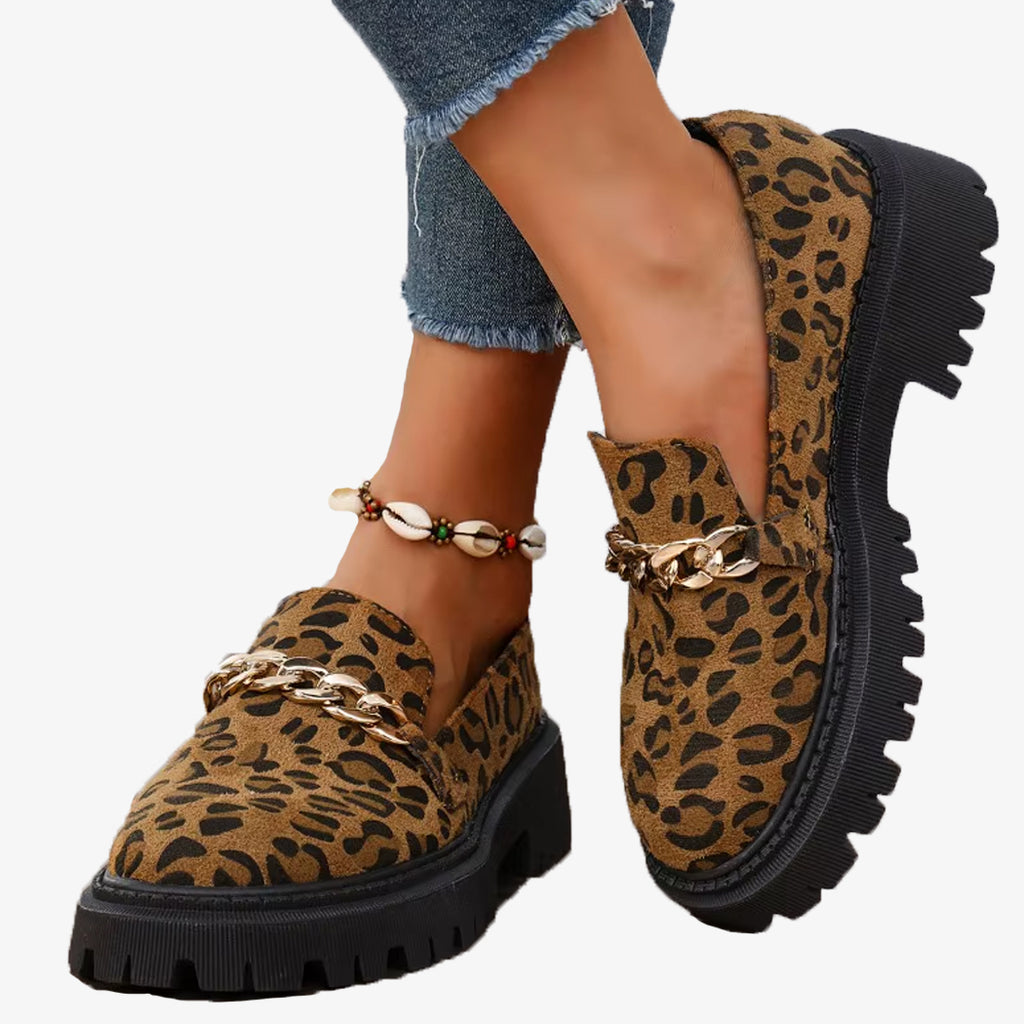Paar Mokassins mit Leopardenmuster aus Wildleder und Plateau mit Kette, getragen mit Jeans und Fußkettchen aus Muscheln