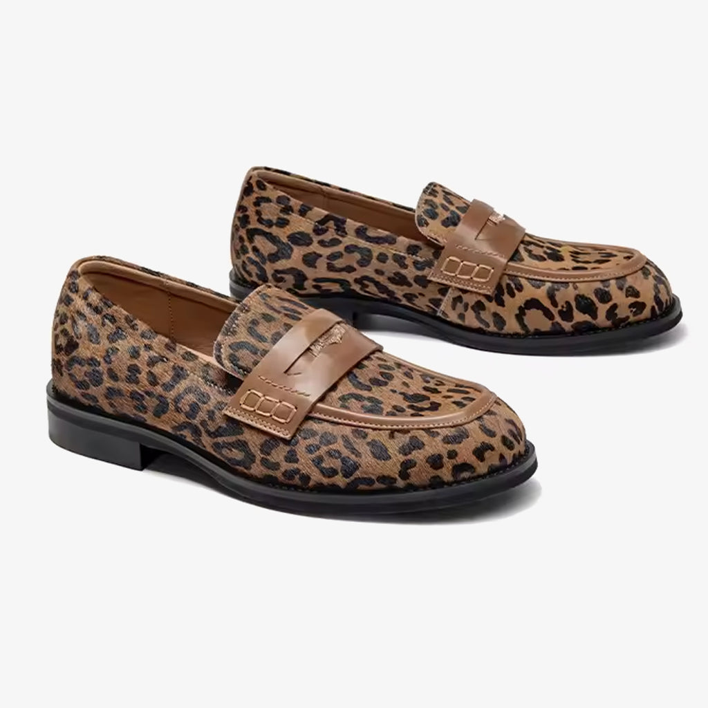 Paar Mokassins mit Leopardenmuster aus Leder mit Riemen über dem Spann vor weißem Hintergrund