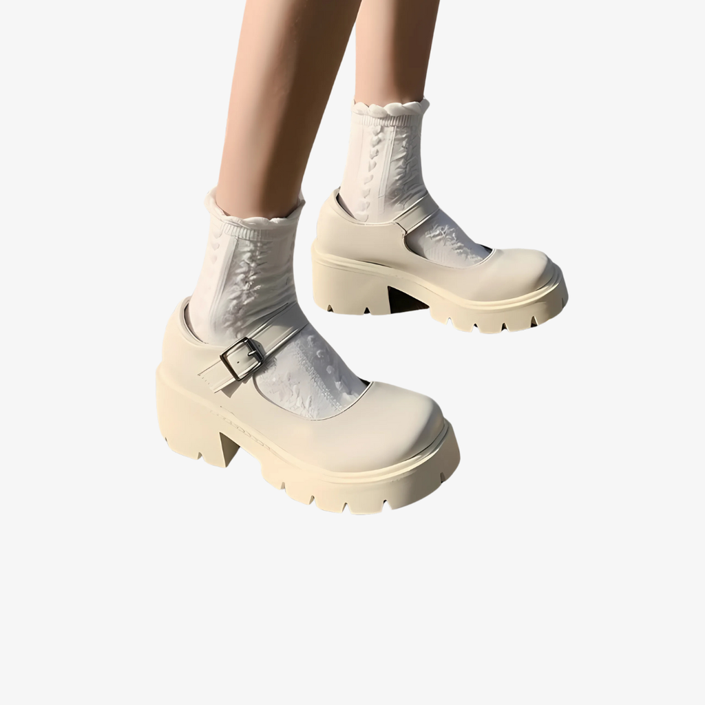 Frau, von der nur die Beine zu sehen sind, trägt beige Plateau-Mokassins mit einem Riemchen darüber und weiße Socken.
