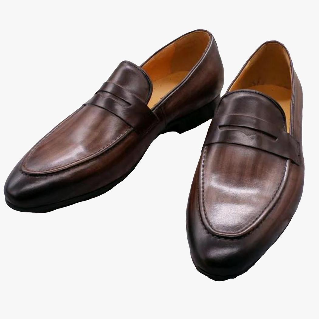 Auf hellgrauem Hintergrund sieht man ein Paar dunkelbraune Loafer für Herren aus Echtleder
