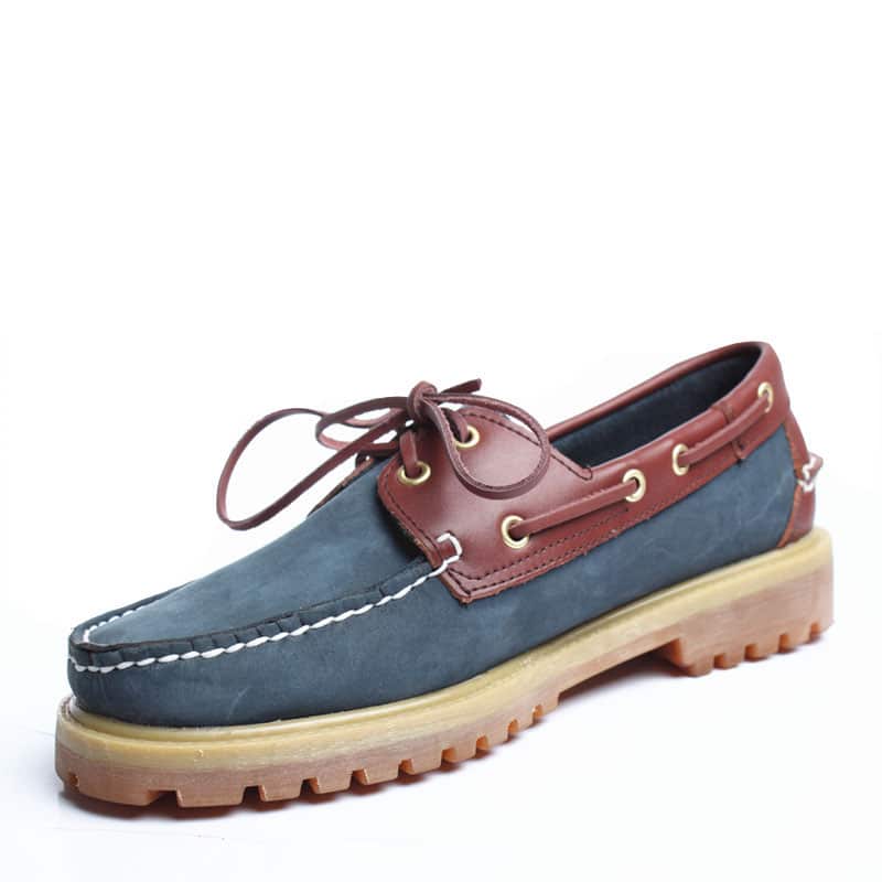 Blauer und brauner Boot-Mokassin auf weißem Hintergrund.