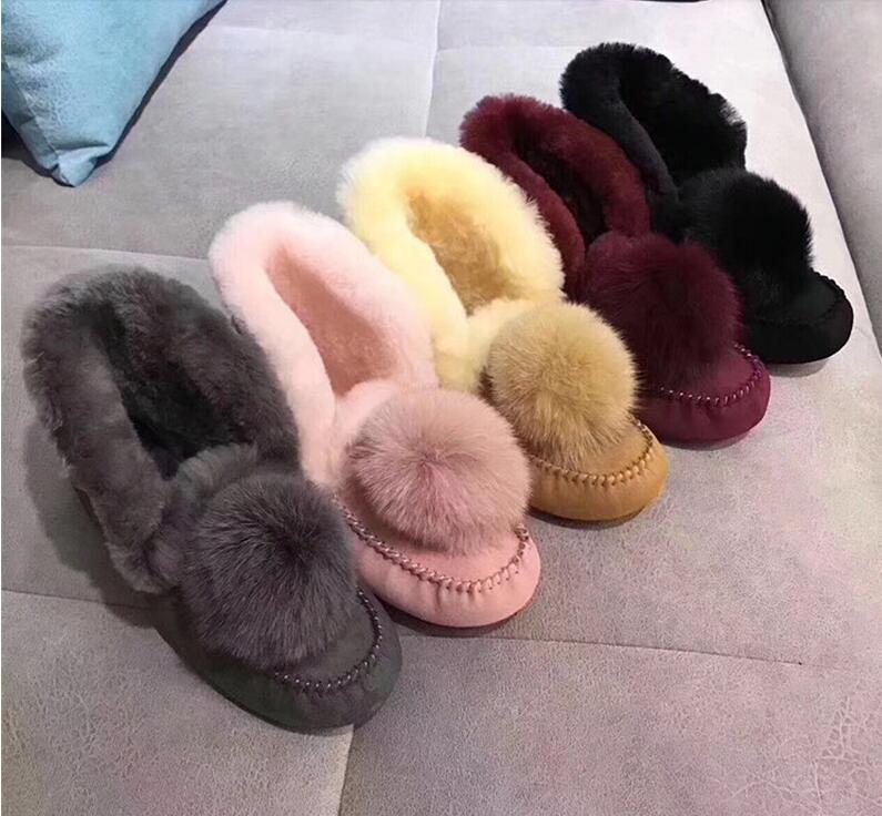 Indische Wintermokassins aus gefüttertem Wildleder mit Pompons, in verschiedenen Farben, auf einem Sofa liegend