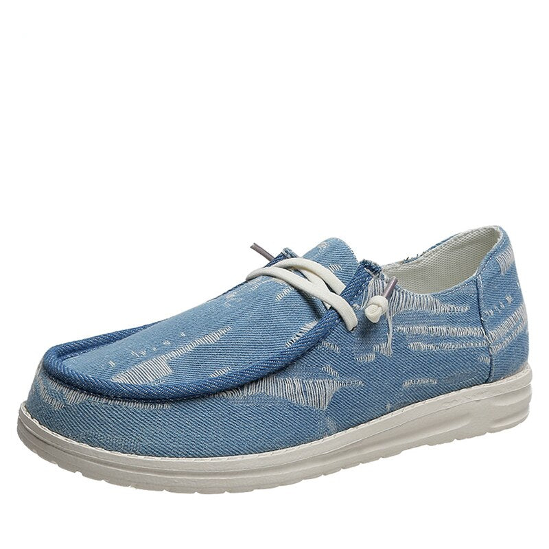 Mokassin im Bootsstil mit Schnürsenkeln in blauem Jeansstoff auf weißem Hintergrund