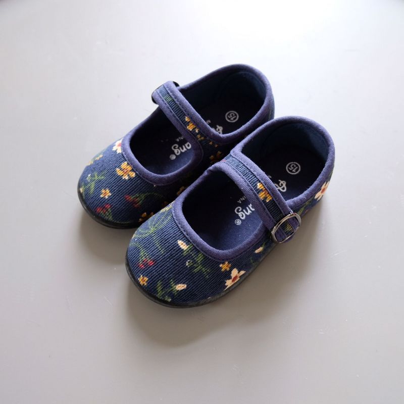 blauer Kindermokassin aus Cord auf grauer Wand