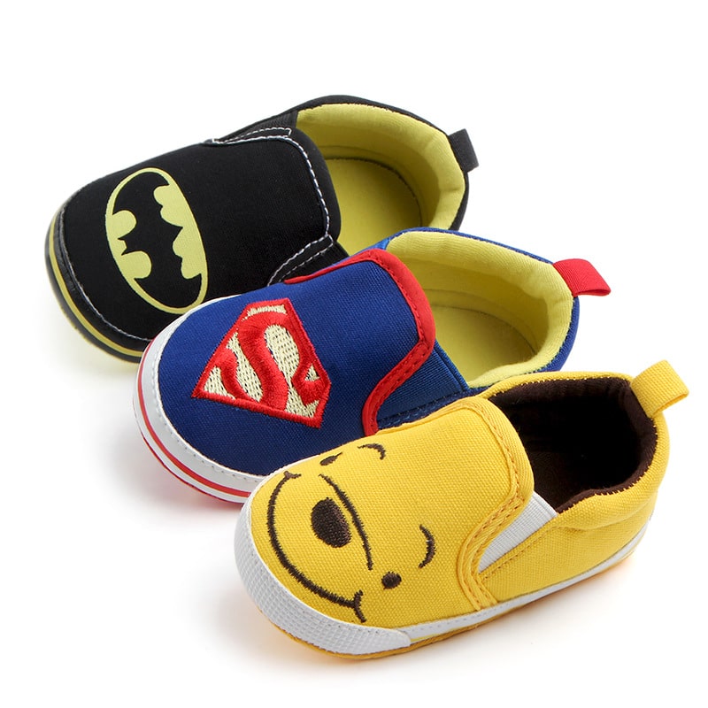 Auf weißem Hintergrund sind drei Mokassins aus Leinen mit Batman in Schwarz, Spiderman in Blau und Winnie the Pooh in Gelb abgebildet.