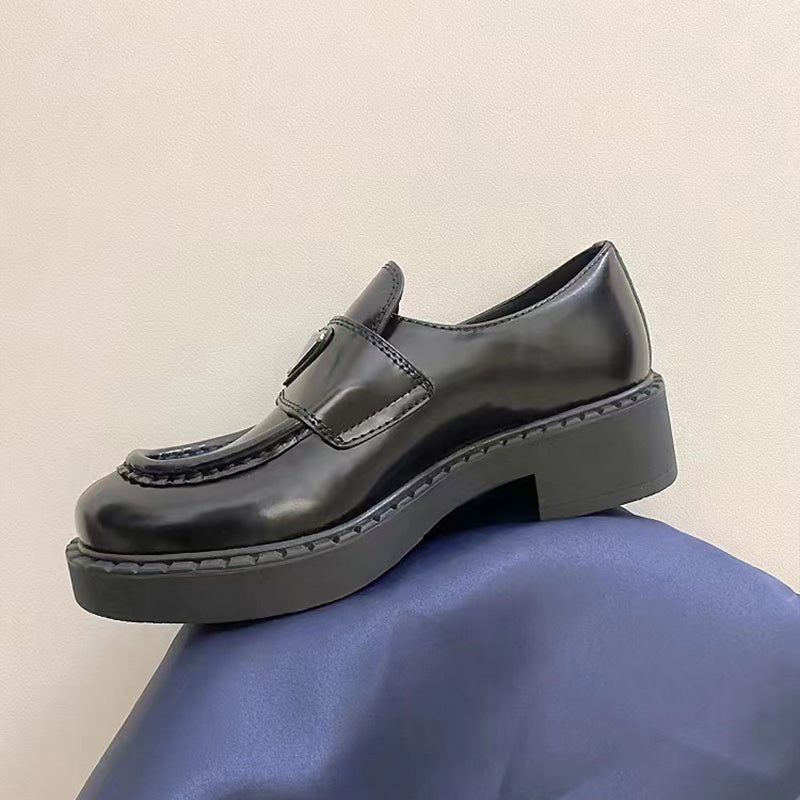 schwarzer Ledermokassin auf blauem Boden