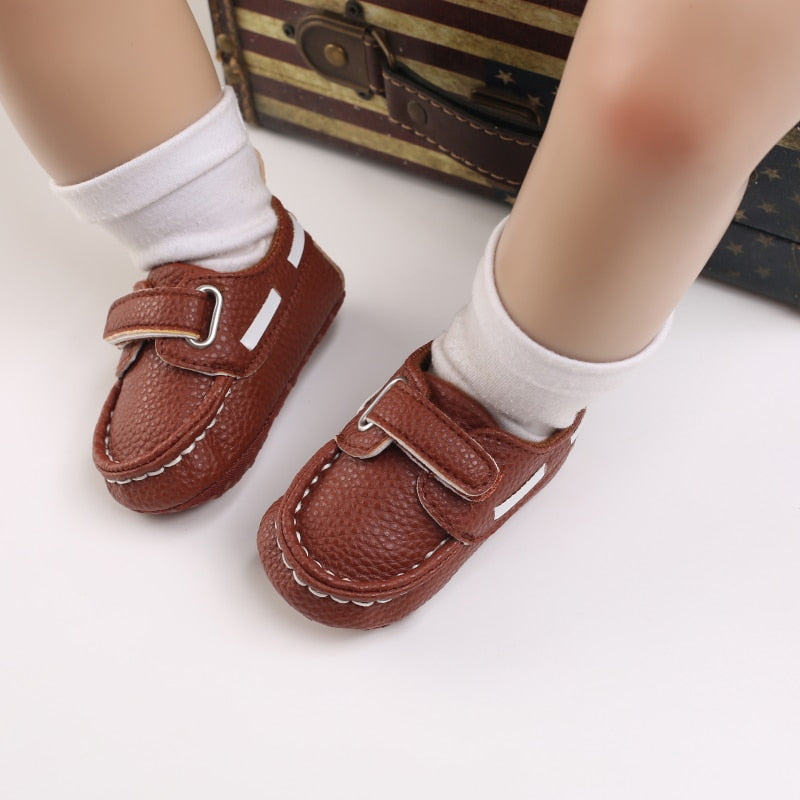 Baby mit weißen Söckchen und braunen Mokassins im Bootsstil