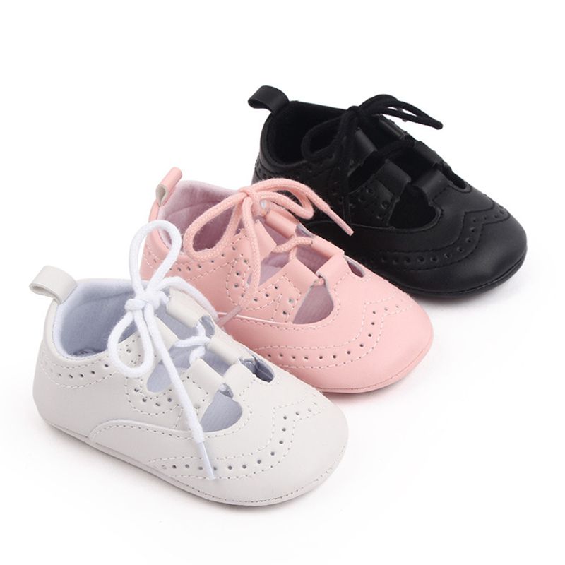 Drei diagonal ausgerichtete Baby-Mokassins mit Schnürsenkeln in den Farben Weiß, Rosa und Schwarz