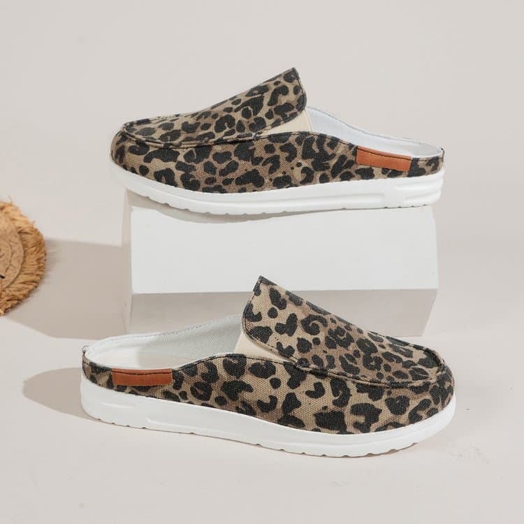 Im Profil dargestellt, ein Paar runde Sportmokassins aus Leinen mit Leopardenmuster und einer dicken weißen Sohle. Ein Schuh steht auf einem weißen Display und einer darunter auf einem weißen Boden