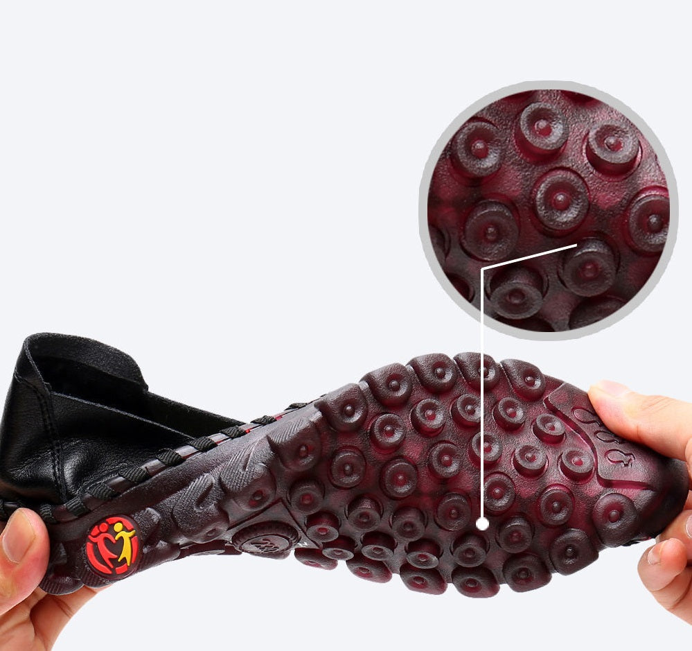 Gekreuzte Beine mit roten Schuhen an den Füßen neben anderen braunen, schwarzen und weißen Schuhen.