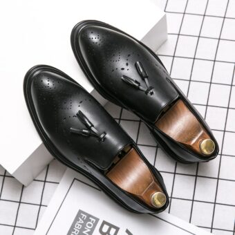 Ein Paar schwarze Mokassins mit Lederquaste auf einem weißen Schuhkarton