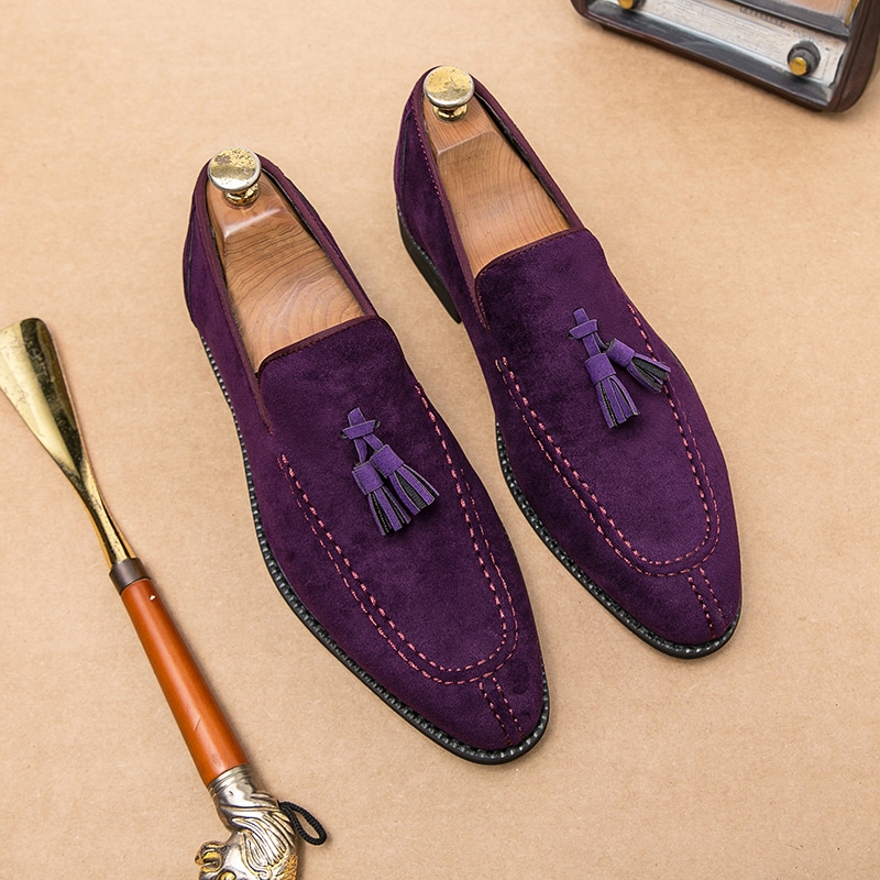 Ein Paar violette Mokassins mit Pompons und einem Schuhanzieher an der Seite.