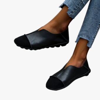 Ein Paar weiche Mokassins mit runder Spitze aus rotem Wildleder und Glattleder mit sichtbaren Nähten, getragen zu Jeans auf hellgrauem Fliesenboden