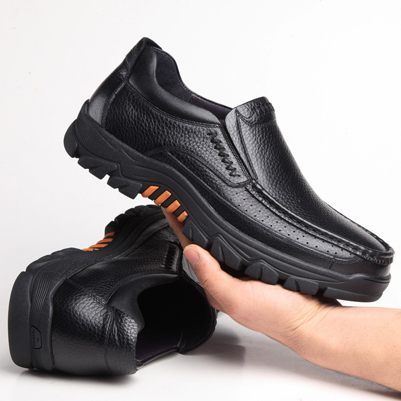 Foto von einem Paar orthopädischer Mokassins aus schwarzem Leder mit dicker Sohle, ein Schuh liegt auf dem Boden, der andere wird in einer Hand gehalten.