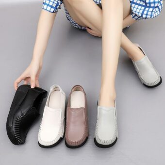 Bein einer Frau mit grauen Schuhen an den Füßen mit anderen Schuhen neben ihr, schwarz, weiß und braun