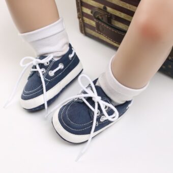 Babybeine mit weißen Socken und blauen Mokassins im Bootsstil