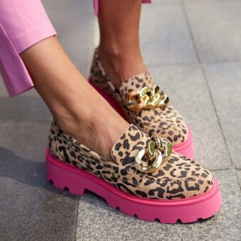 Fuß einer Frau, die eine rosafarbene Hose und Leopardenmokassins mit rosafarbener Sohle trägt