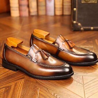 on voit sur un fond marron une paire de mocassins à glands en cuir véritable pour homme