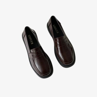 Paire de mocassins élégants marrons, sur fond gris clair.