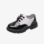 Un mocassin fermé pour enfant, noir brillant avec une partie blanche